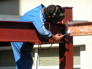 person welding steel beams by hand on a construction site
