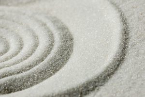 Raked sand background pattern and texture in a Japanese zen garden with concentric circles for meditation, tranquility and wellness.