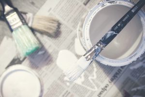 bucket of white paint with paintbrush sitting on top