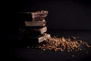 small stack of dark chocolate chunks covered in chocolate shavings on a dark background